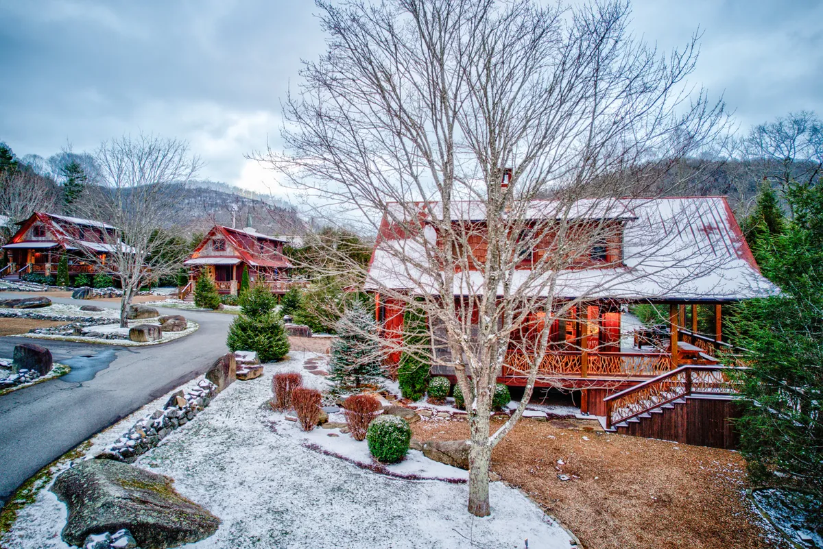A serene winter scene of log cabins nestled among snow-covered trees, with an expansive natural landscape surrounding them. The cabins' rustic exteriors blend harmoniously with the environment, embodying a peaceful, nature-focused getaway that supports outdoor exploration and sustainable living.