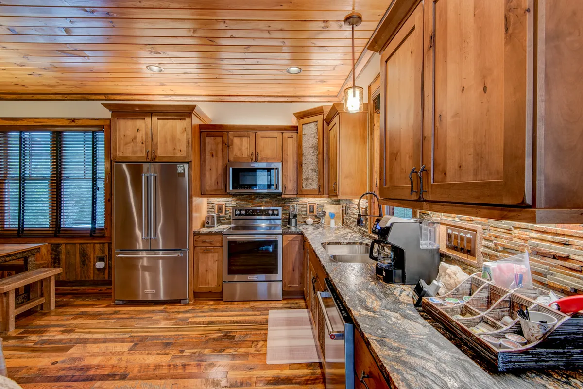 A gourmet kitchen featuring stainless steel appliances, granite countertops, wooden cabinetry, and a central island. The space is both functional and inviting, designed for everything from casual breakfasts to elegant dinners.